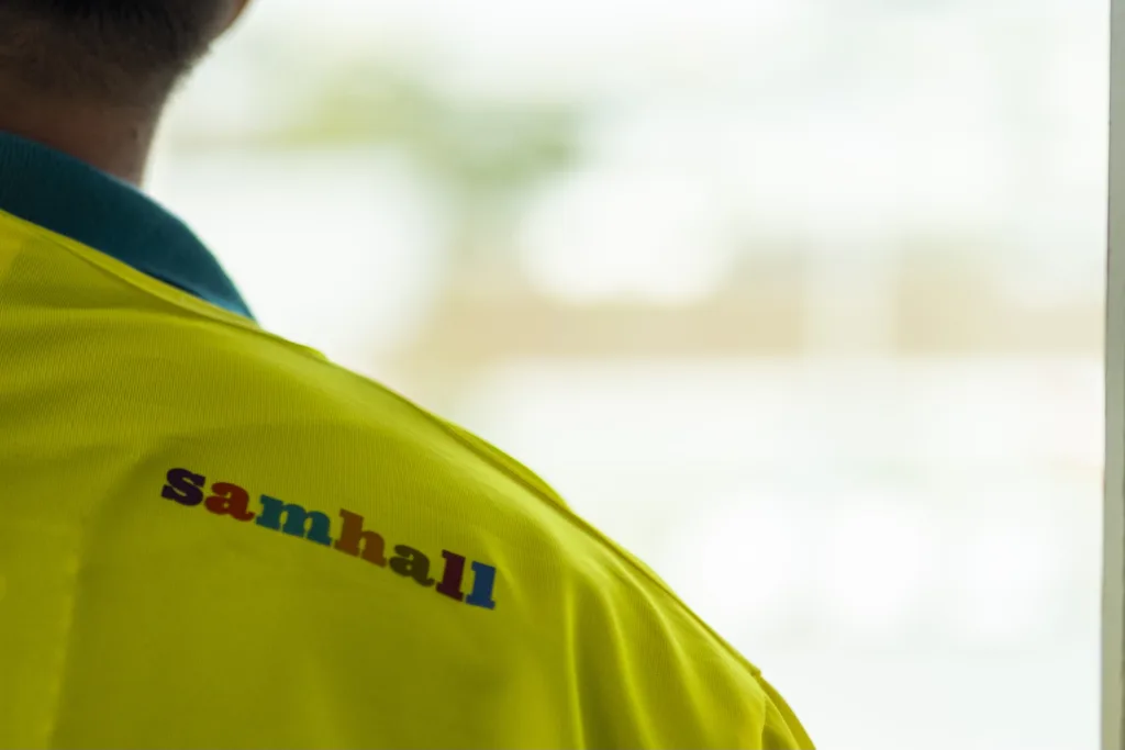 Fotot zoomar in en Samhall-logga på en gul tröja.