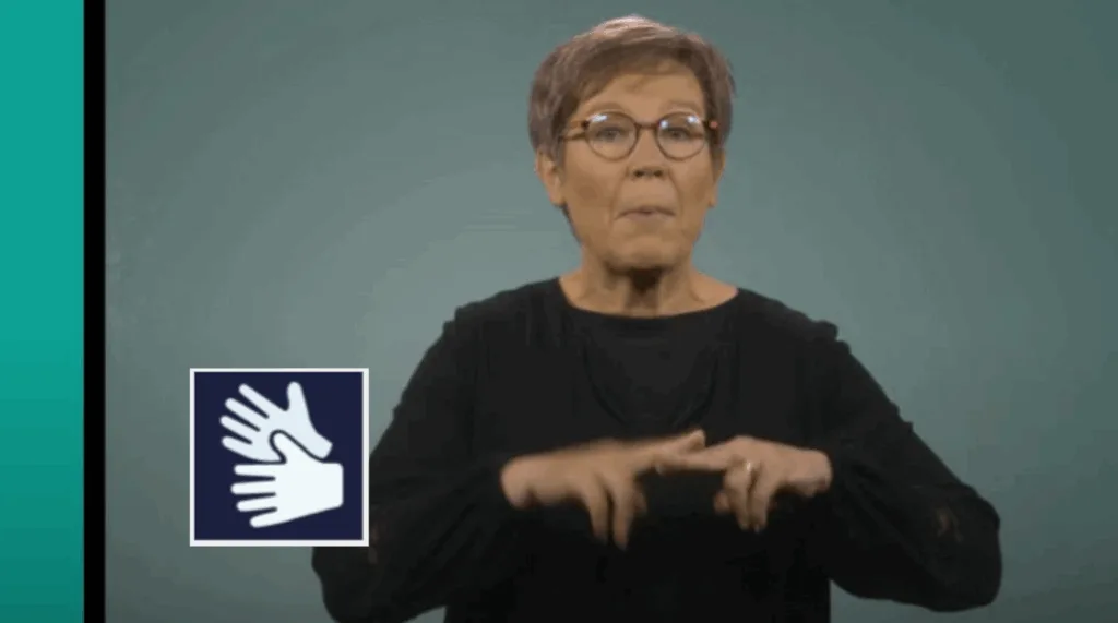 Skärmdump från film med teckenspråkstolken i bild. Loggan för teckenspråk ligger till vänster i bilden.