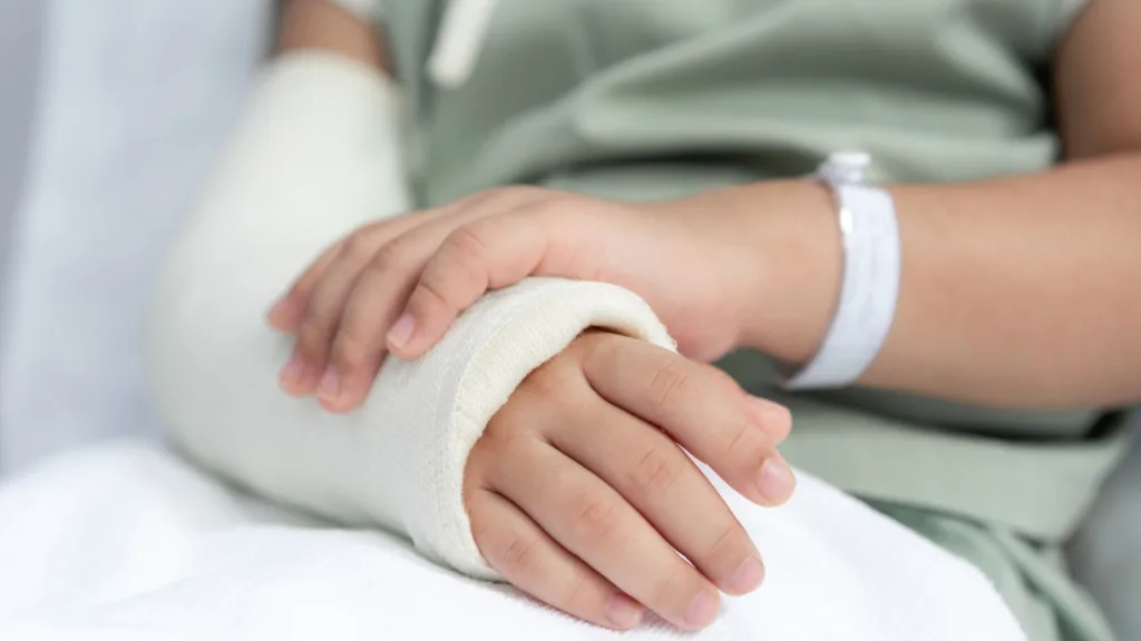 En person har högerhanden i gips. Hen bär en grön T-shirt och ett vitt armband på vänster arm.