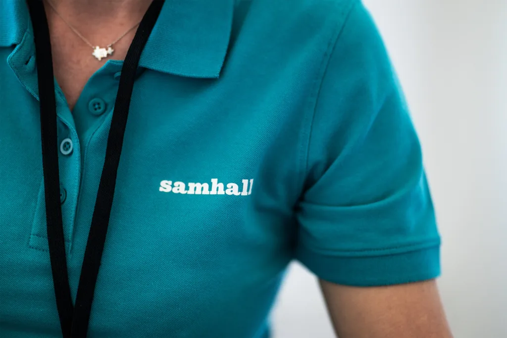 Inzoomad vit Samhall-logga på en blå tröja.