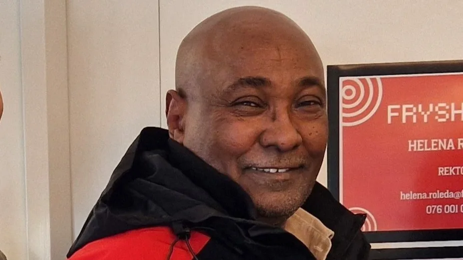 Yakim ler och tittar in i kameran. Han har en röd och svart jacka på sig.