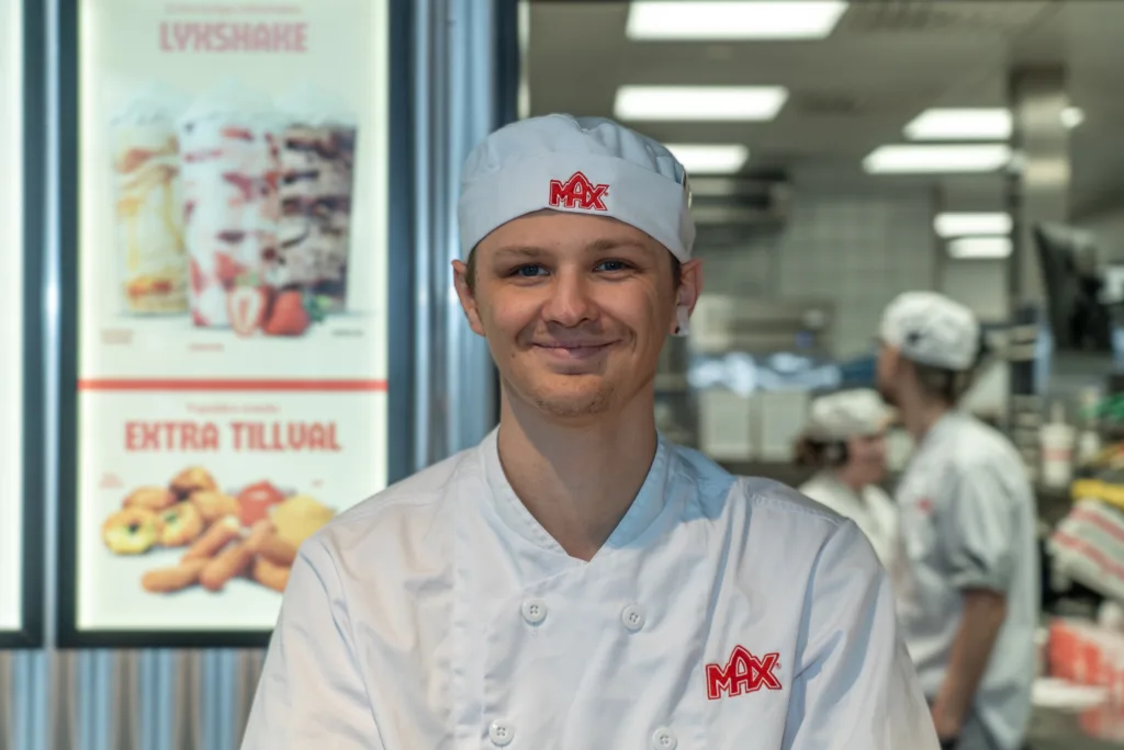 Kim Koskela i vita Max-kläder. Man ser köket i bakgrunden.